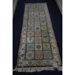 A MODERN COTTON RUNNER, cream ground, pastel shade squares to the centre, each with a foliate motif,