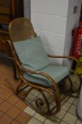 A BENTWOOD ROCKING CHAIR, with cane work back and seat with removable cushions