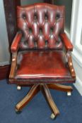 A BURGUNDY BUTTON BACK SWIVEL OFFICE/STUDY CHAIR, on a mahogany frame
