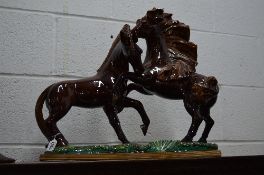 A LARGE CERAMIC FIGURE GROUP OF TWO PRANCING HORSES ON A RECTANGULR BASE, brown and iridescent green