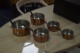 A SET OF FIVE COPPERED GRADUATED PANS