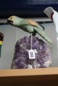 A CARVED ORIENTAL HARDSTONE PARROT, mounted on an amethyst geode, height approximately 23.5cm (