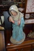 AN EARLY 20TH CENTURY PAINTED PLASTER FIGURE OF THE VIRGIN MARY, modelled kneeling in prayer,