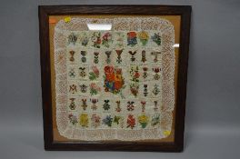 A LARGE GLAZED FRAME CONTAINING A NUMBER OF WWI ERA SILK PATCHES OF MILITARY MEDALS AND FLOWERS,