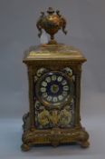 A LATE 19TH CENTURY CONTINENTAL BRASS AND PAINTED CASE MANTEL CLOCK, urn finial above a foliate cast