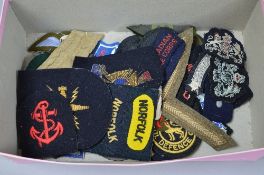 A BOX CONTAINING A NUMBER OF CLOTH WWII ERA UNIT PATCHES, shoulder titles, chevrons, etc, British