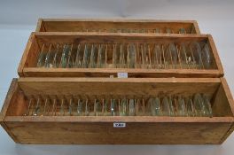 THREE WOODEN TRAYS WITH DIVISIONS CONTAINING WATCH AND CLOCK CRYSTALS, approximately one hundred and