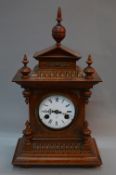 A LATE 19TH CENTURY WALNUT CASED MANTEL CLOCK OF ARCHITECTURAL FORM, white enamel dial with Roman
