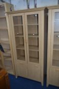 A MODERN OAK EFFECT BOOKCASE, with two glazed doors over two cupboard doors, approximate size height
