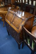 AN OAK FALL FRONT BUREAU, with two drawers below, an ink stand, blotter and a letter rack inside (