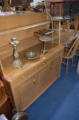 A LIGHT OAK EXTENDING DINING TABLE, seven spindle back chairs and a matching sideboard with raised