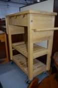 A MODERN BEECH KITCHEN TROLLEY, with three drawers, one drop end and towel rail