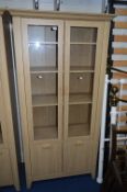 A MODERN OAK EFFECT BOOKCASE, with two glazed doors over double cupboard doors, approximate height