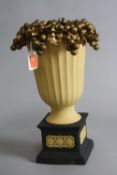 A WEDGEWOOD BLACK AND CANE JASPERWARE PEDESTAL VASE, with plastic vine and grape decoration to