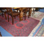 A 20TH CENTURY AFGAN WOOLLEN RUG, red ground with black multi strap border and central geometric