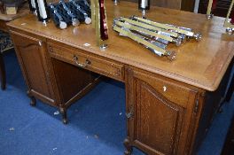 AN OAK CONTINENTAL STYLE KNEE HOLE DESK, with one drawer central to two cupboard doors,