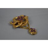 A VICTORIAN AMETHYST SCROLL KNOT BROOCH, with an oval drop pendant and swag chains, hair compartment