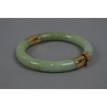 A MODERN JADE BANGLE, round hinged design with two pale green jadeite hooped sections, each capped