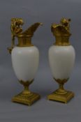 A PAIR OF CONTINENTAL ORMOLU AND WHITE MARBLE EWER MANTELPIECE ORNAMENTS, the handle cast as cherubs