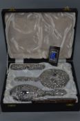 AN ELIZABETH II SILVER BACKED LADIES FOUR PIECE DRESSING TABLE SET, embossed foliate decoration,