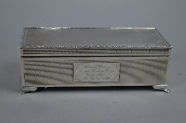 AN ELIZABETH II RECTANGULAR SILVER TABLE TOP CIGARETTE BOX, foliate cast rim, engine turned