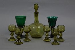 A LATE 19TH CENTURY GREEN GLASS LIQUEUR SET, comprising onion shaped decanter with swirl stopper and