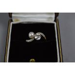 AN EARLY 20TH CENTURY DIAMOND AND CULTURED PEARL CROSSOVER DESIGN RING, to diamond set engraved