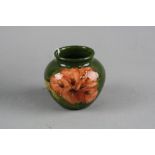 A SMALL MOORCROFT POTTERY BULBOUS VASE, Hibiscus pattern on green ground, impressed marks and faded