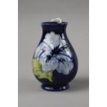 A SMALL MOORCROFT POTTERY VASE, 'Hibiscus' pattern on blue ground, impressed marks to base, height