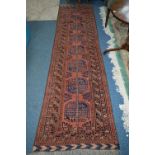 A 20TH CENTURY AFGHAN CARPET RUNNER, russet ground, multi strap border and central geometric motifs,