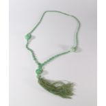 A long jade and green glass bead necklace, c.1920s, with silk tassel.