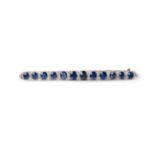 A sapphire and diamond slender oblong brooch, claw mounted with twelve oval cut graduated sapphires,