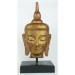 A gilt wooden Buddha's head, late 20th/early 21st century, on ebonized base, 71cm high Note: There