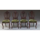 A set of four Edwardian shield back chairs with pierced floral splats, above overstuffed seats,