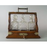 An Edwardian oak and brass mounted tantalus, with three glass decanters, v36.