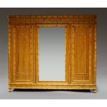 An Edwardian pitch pine triple wardrobe, with turned faux bamboo moulding to doors and cornice,