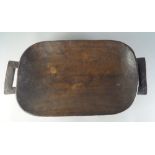 A twin handled tribal hardwood oblong dish, 20th century, resting on four feet,