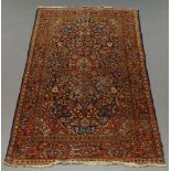 A Kashan rug with red pole medallion in a floral and foliate indigo field, red main border,