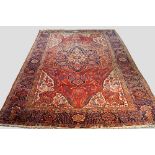 A Heriz carpet with flowerhead pole medallion in a brick red field with ivory spandrels and