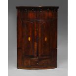 A George III mahogany bow front corner cupboard, with a pendant ball frieze, over two doors,