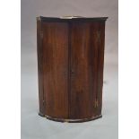 A mahogany bow fronted hanging corner cupboard, 19th century,