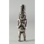 A South American silver figure of a man, wearing a tall hat, with arms crossed over his chest,