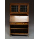 An Edwardian oak Arts and Crafts bureau bookcase, green glazed leaded pannels,