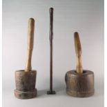 Two tribal mortars, with pestles, together with na walking cane, mounted on a metal stands,