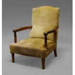 An Arts and Crafts oak armchair, with pale brown flock type upholstery,