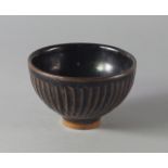 A Japanese studio pottery bowl, 20th century, decorated with tenmoku glazes on a ridged surface,