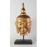 A gilt wood Buddha's head, late 20th century, on a wooden base,