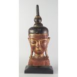 A gilt wood Buddha's head, late 20th century, on a wooden base,