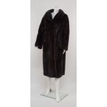 A full length dark mink coat, rounded collar and concealed fastening,