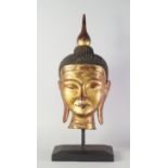 A gilt wood Buddha's head, late 20th century, on a wooden base,